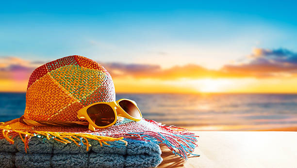 Colorful straw hat, a yellow sunglasses and blue towel in sunshine. Summer vacation image with copy space.